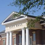 Exterior view of a city hall building with columns and a clear blue sky