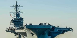America To Build New Powerful Supercarrier Aircraft carrier guided by tugboats in a harbor