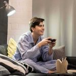 Teen in pajamas playing video games on a couch