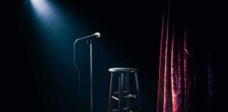 Microphone on stand beside stool under spotlight on stage