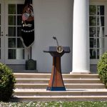 Kennedy Center Board Defies Judge and Votes Trump’s Name Back on Building Podium with presidential seal in a garden colonnade