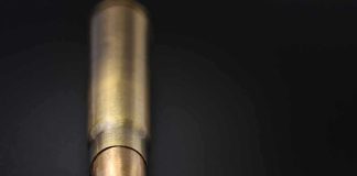 Close-up of a single brass bullet on a dark surface