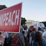 Protest crowd with signs outside a government building; Nate Solder present