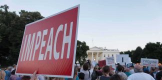 Protest crowd with signs outside a government building; Nate Solder present