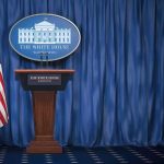 Trump Reveals What Putin Told Him About Ukraine White House press briefing podium with U.S. flag and blue curtain