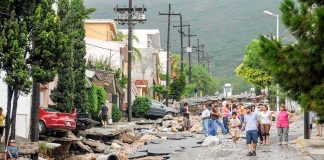 Residents walk along a heavily damaged street after a disaster