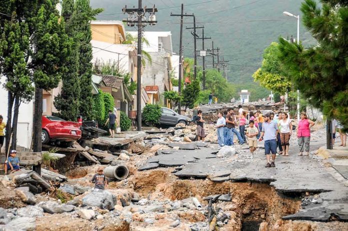 shutterstock_1165722466 Residents walk along a heavily damaged street after a disaster