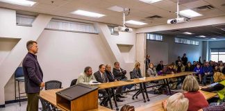 Roger Marshall addresses a community meeting with Apostolos Doxiadis among attendees
