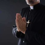 Priest Killed in Attack at Historic Polish Abbey Clergyman in black robe praying with hands together