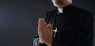 Priest Killed in Attack at Historic Polish Abbey Clergyman in black robe praying with hands together