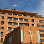 Brick hospital building with cross and statue
