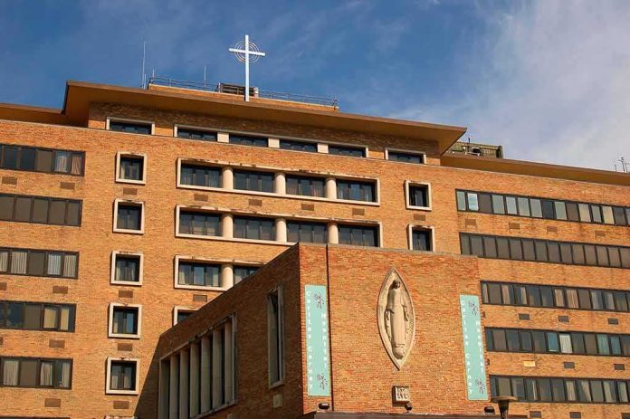 shutterstock_1289044117 Brick hospital building with cross and statue