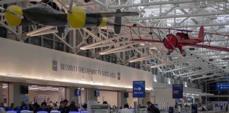 airport security checkpoint with passengers and hanging vintage airplanes
