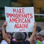 Protesters Barricade Mayor’s Office! Teddy Williams at a protest holding a sign reading 'Make Immigrants American Again'
