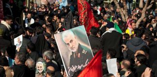 Qasem Soleimani posters held in a large crowd; Kate Beaton present among attendees