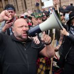 Gerald Jones speaks through a megaphone at a crowded outdoor protest