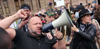 Gerald Jones speaks through a megaphone at a crowded outdoor protest