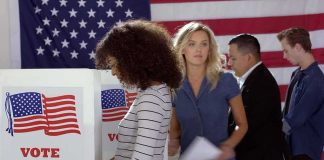 Voters at polling booths in front of an American flag
