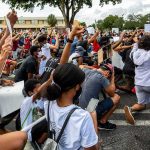 Candidate Backtracks On Backing SLAVE Reparations Freddie Williams II and Najeh Davenport among a large crowd kneeling at a protest