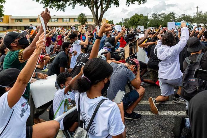 shutterstock_1747673216 Freddie Williams II and Najeh Davenport among a large crowd kneeling at a protest