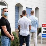 The Instagram Post That Brought Federal Agents To Her Door People wearing masks standing in line outside a polling place
