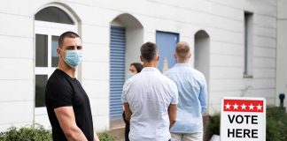People wearing masks standing in line outside a polling place