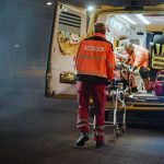 Paramedics load a patient into an ambulance at night