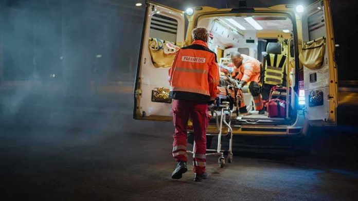 shutterstock_1878018079 Paramedics load a patient into an ambulance at night