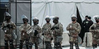 Line of soldiers in riot gear standing on a city street