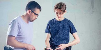 Two people at a table handling a handgun with safety glasses on