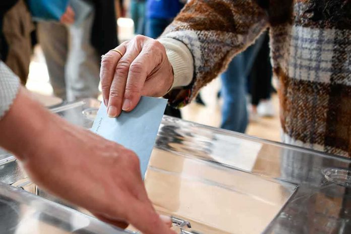 shutterstock_2147812199 Hand inserting ballot into transparent box