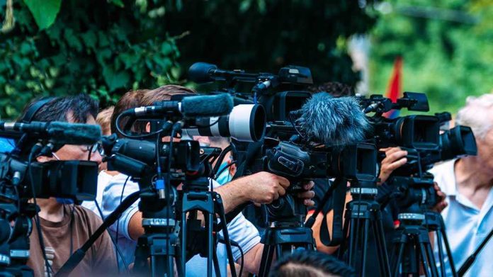 shutterstock_2210577723-2 TV news cameras crowding together at an outdoor event