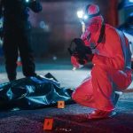 forensic investigator photographs crime scene evidence at night
