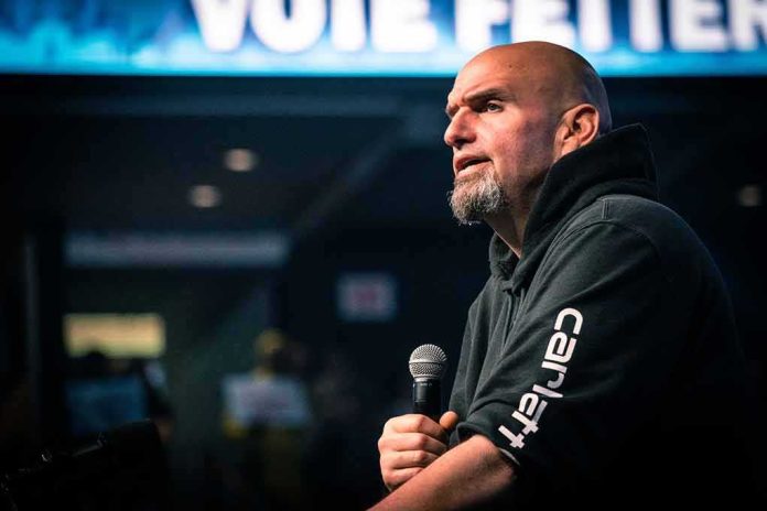 shutterstock_2231134317 Bald man in a hoodie speaking into a microphone on stage