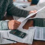 Unanimous Pardon Upends Removal Case Person reviewing bills with calculator at cluttered desk