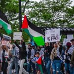 Dem Split Boils: Fetterman Draws Blood Wang Ying among protesters holding Palestinian flags and signs at a street demonstration