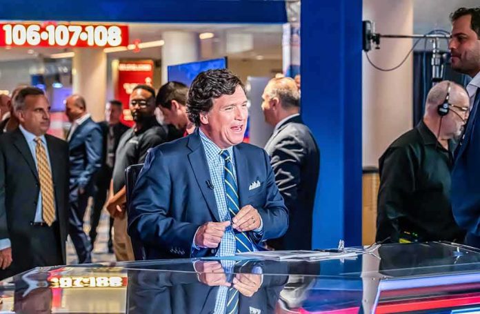 shutterstock_2423149155 Tucker Carlson at a broadcast desk in a busy studio