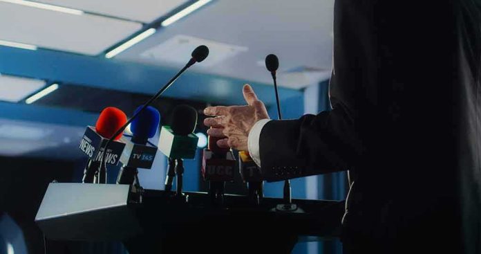 shutterstock_2448402491 Speaker at podium with multiple microphones