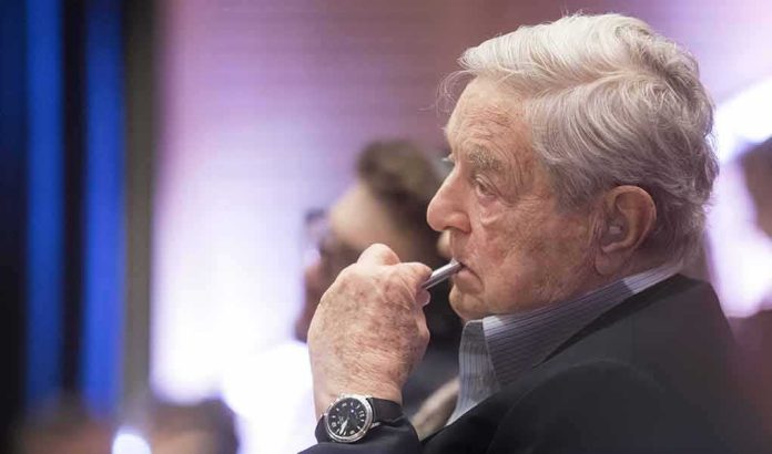 shutterstock_273485108 George Soros in profile, holding a pen to his lips during an event