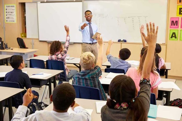 shutterstock_388667902 Teacher at front of classroom as students raise hands