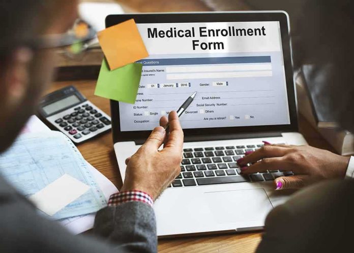shutterstock_494575816 Laptop displaying a medical enrollment form with two people reviewing it