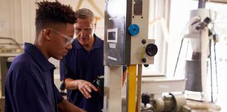 Student operating a bandsaw under instructor supervision