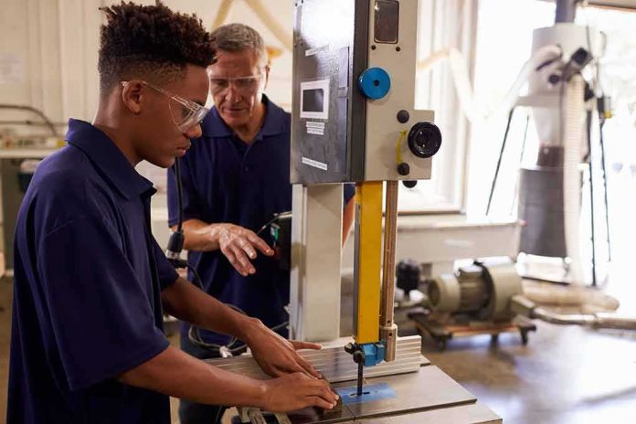 shutterstock_531129046 Student operating a bandsaw under instructor supervision