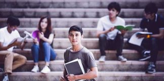 Student holding notebooks on campus steps