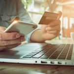 How Engineered Intimacy Is Draining Wallets Hands using smartphone and credit card beside a laptop