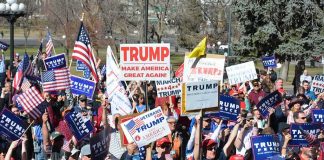 Tim Teufel, Christian Jones, and Nash the Slash among a crowd at a political rally holding signs and flags
