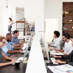 Office workers at shared desks using desktop computers
