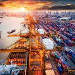 Container port with cranes and cargo ships at sunset