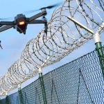 The Technology That Changed Prison Smuggling Drone flying near barbed wire security fence