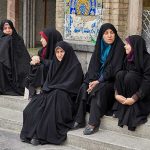 Zahra Rahnavard among women in black chadors sitting on stone steps
